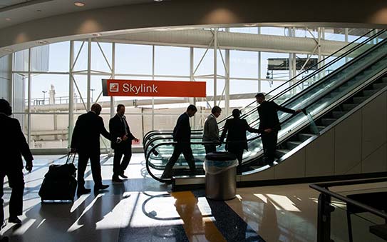 Business people riding escalator in airport